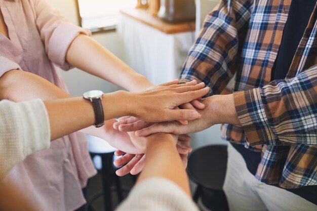 Image en gros plan de l'équipe commerciale debout et joignant leurs mains au bureau