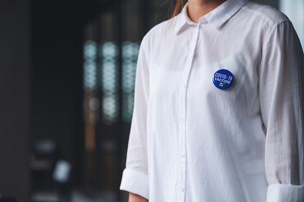 Image en gros plan d'une femme avec une broche de signe vaccinée Covid19 sur la chemise