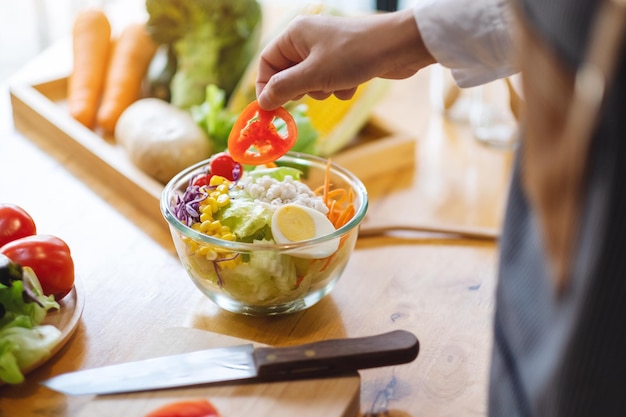 Image en gros plan d'une femme chef cuisinant une salade de légumes frais dans la cuisine