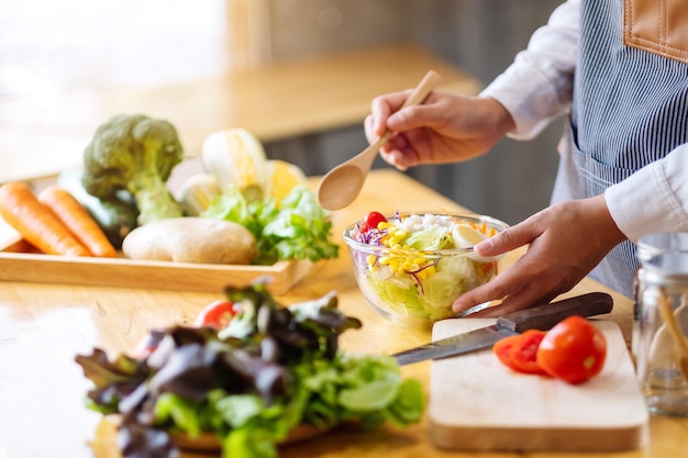 Image en gros plan d'une femme chef cuisinant et tenant un bol de salade de légumes frais à manger dans la cuisine