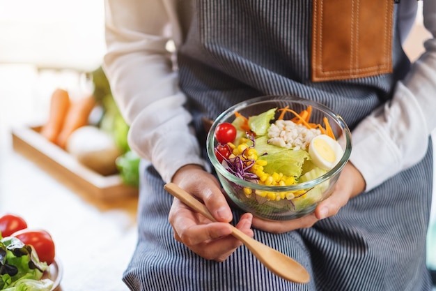 Image en gros plan d'une femme chef cuisinant et tenant un bol de salade de légumes frais à manger dans la cuisine