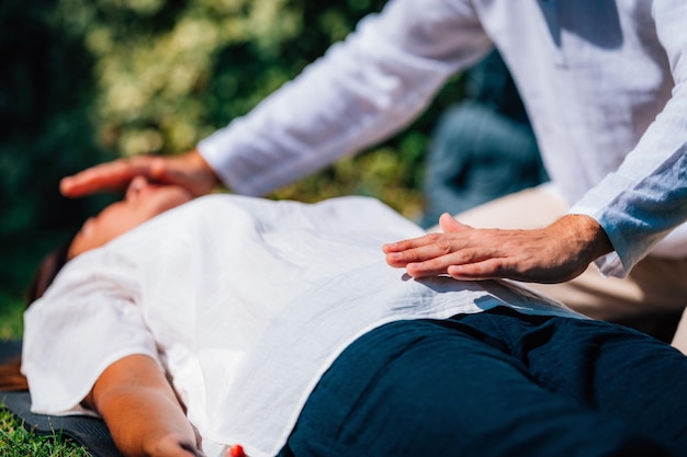 Photo image en gros plan d'une femme détendue allongée avec les yeux fermés et subissant un traitement de guérison au reiki