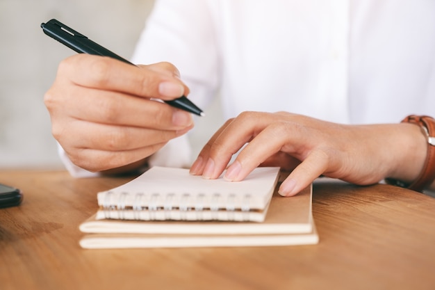 Image en gros plan d'une femme écrivant sur un cahier vierge sur une table en bois