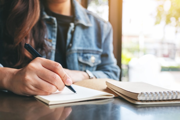 Image en gros plan d'une femme écrivant sur un cahier vierge sur la table