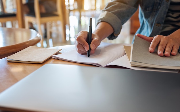 Image en gros plan d'une femme écrivant sur un ordinateur portable avec un ordinateur portable sur la table