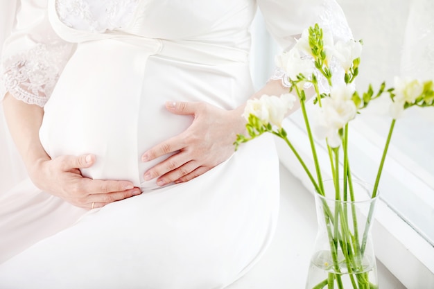 Image en gros plan d'une femme enceinte touchant son ventre avec les mains