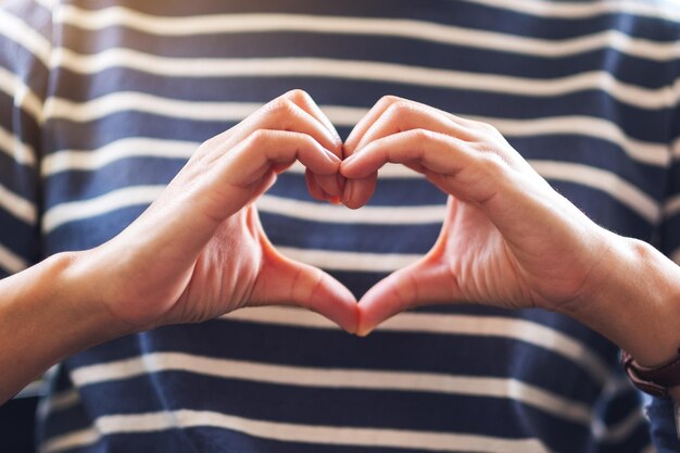 Image en gros plan d'une femme faisant signe de la main du cœur