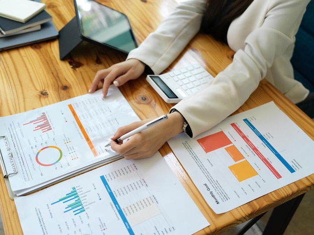 Image en gros plan d'une femme gestionnaire gérant des documents de rapport d'analyse financière sur la table.