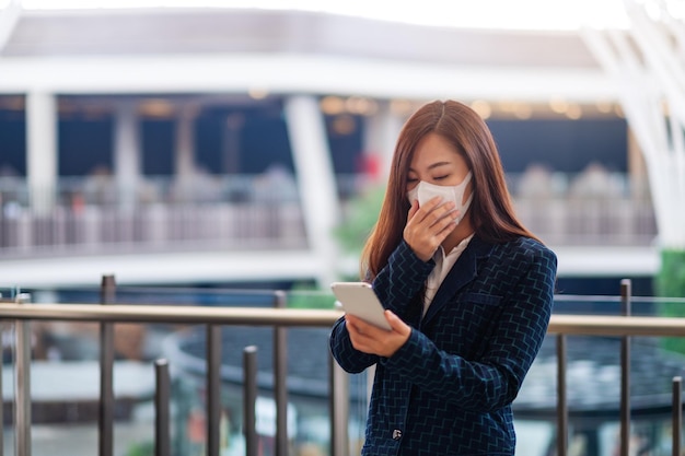 Image en gros plan d'une femme malade portant un masque protecteur, utilisant un téléphone portable pour le concept de soins de santé et de Covid-19