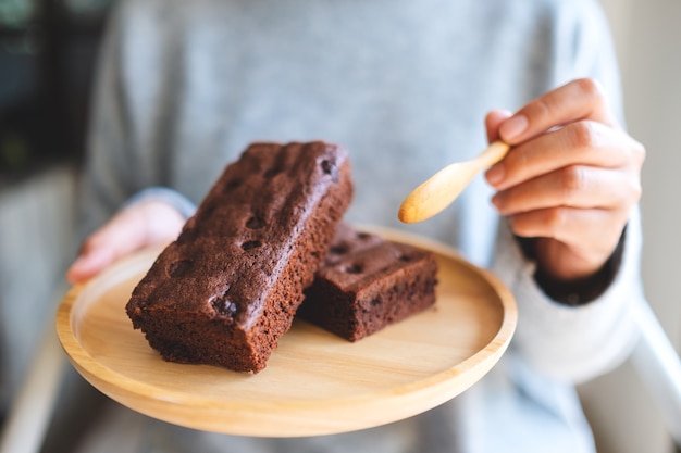 Image en gros plan d'une femme mangeant un délicieux gâteau au brownie avec une cuillère