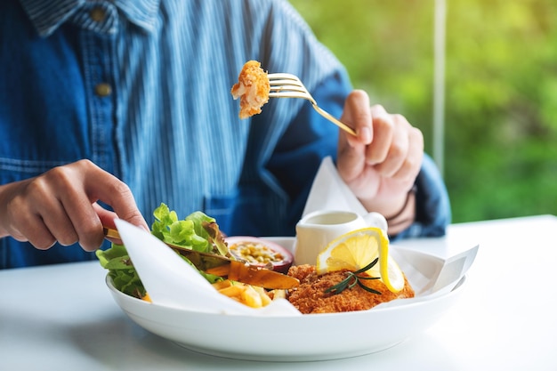 Image en gros plan d'une femme mangeant du poisson et des frites sur la table du restaurant