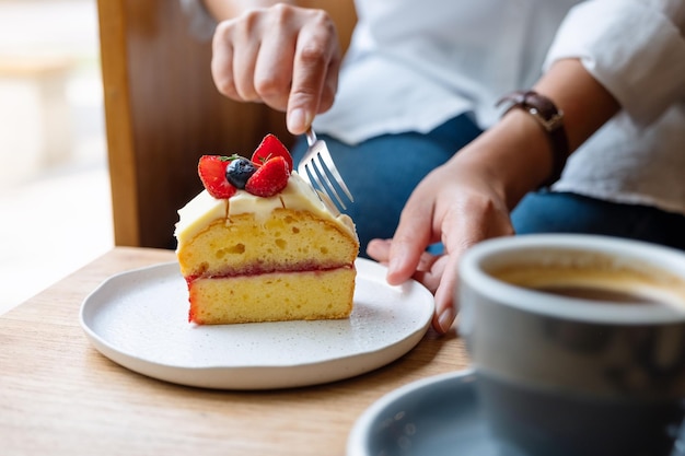 Image en gros plan d'une femme mangeant un gâteau à la fourchette dans un café