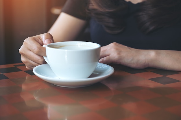 Image gros plan d&#39;une femme tenant et buvant du café chaud au café