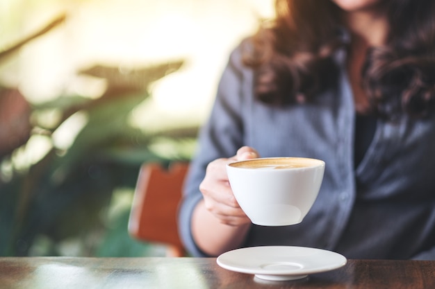 Image gros plan d'une femme tenant et buvant du café chaud au café