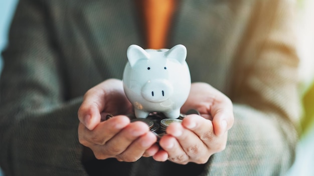 Image en gros plan d'une femme tenant une tirelire et des pièces dans les mains pour économiser de l'argent et un concept financier