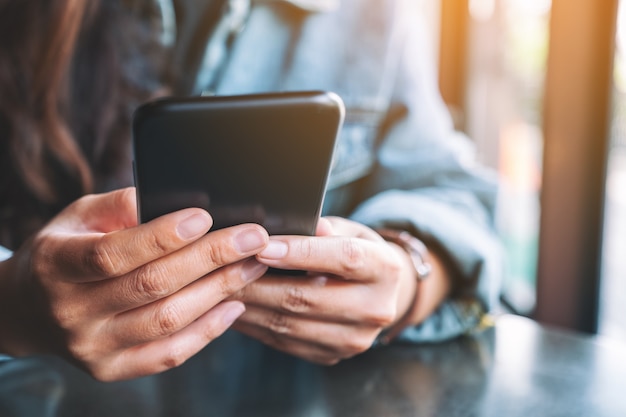 Image en gros plan d'une femme tenant, utilisant et regardant un téléphone portable