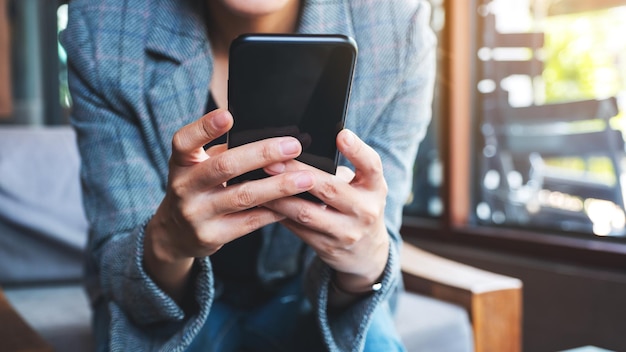 Image en gros plan d'une femme tenant et utilisant un téléphone portable