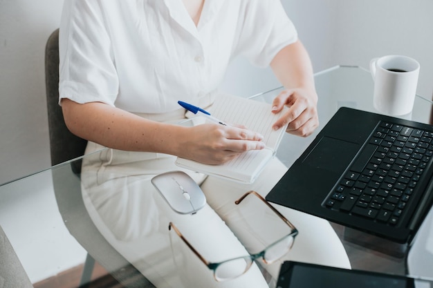 Image en gros plan d'une femme travaillant au bureau à domicile prenant et écrivant à distance des notes et des rendez-vous mains en gros plan Femme indépendante discutant sur Internet sur les réseaux sociaux