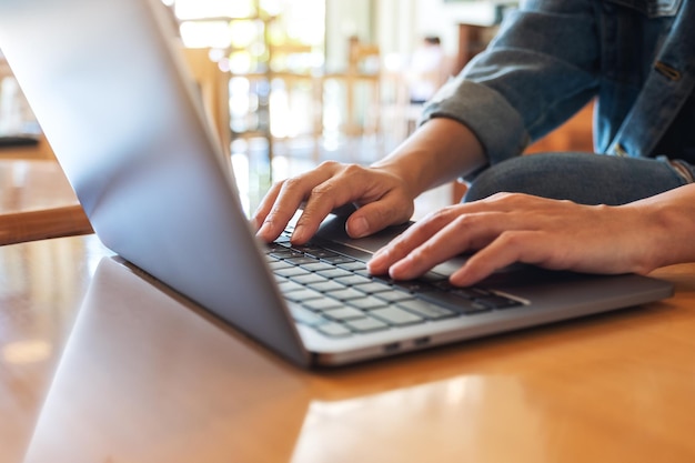 Image en gros plan d'une femme travaillant et tapant sur le clavier d'un ordinateur portable sur la table