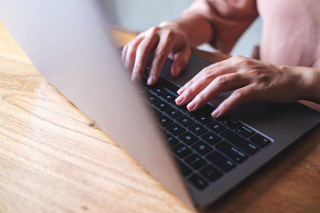 Image en gros plan d'une femme travaillant et tapant sur un clavier d'ordinateur portable sur la table