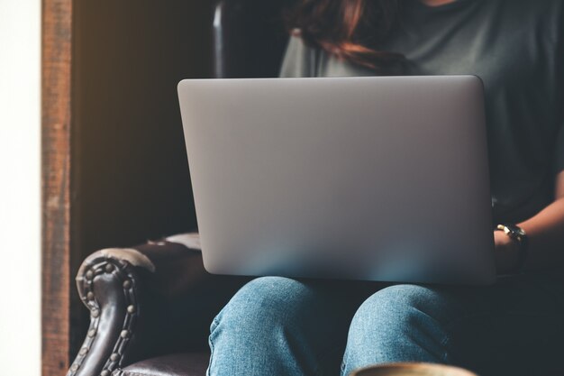Image Gros plan d'une femme travaillant et tapant sur un ordinateur portable assis sur un canapé