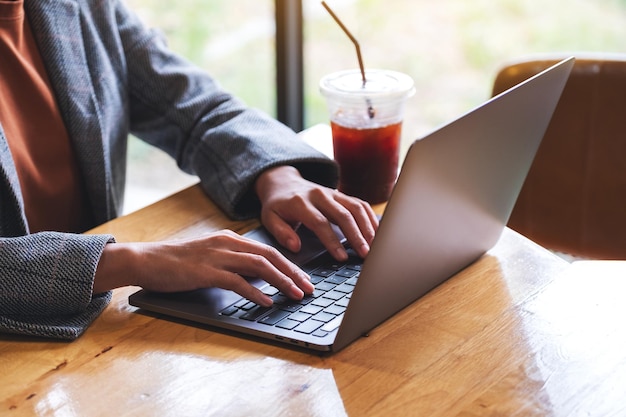 Image en gros plan d'une femme travaillant et tapant sur un ordinateur portable au bureau