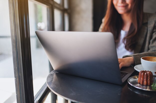 Image en gros plan d'une femme travaillant et tapant sur un ordinateur portable au café