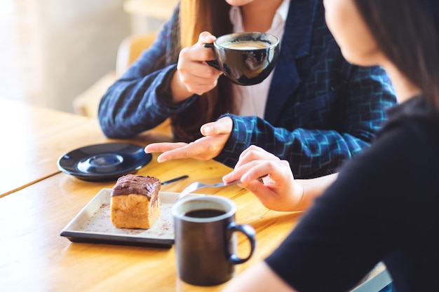 Image en gros plan des femmes ont apprécié de manger un dessert et de boire du café ensemble au café