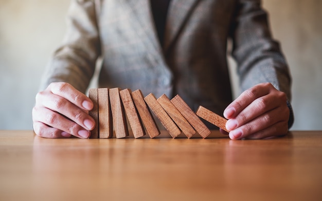 Image en gros plan d'un homme d'affaires essayant de tenir un bloc de bois tout en tombant pour le concept d'entreprise