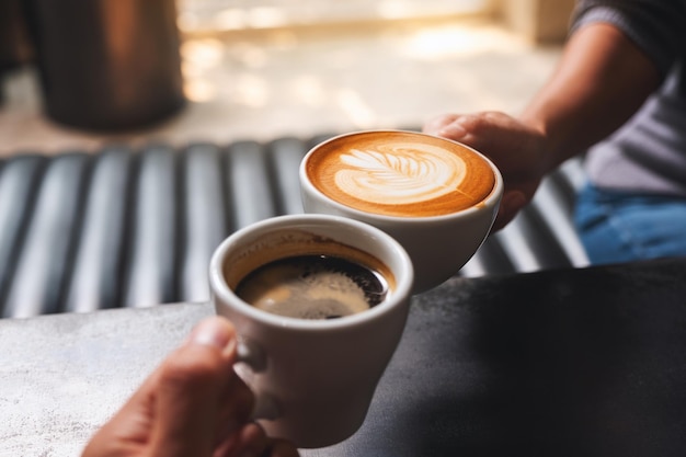Image en gros plan d'un homme et d'une femme faisant tinter des tasses à café blanches dans un café