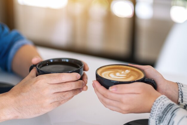 Image en gros plan d'un homme et d'une femme tenant deux tasses de café ensemble