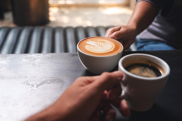 Image en gros plan d'un homme et d'une femme tenant des tasses à café blanches au café