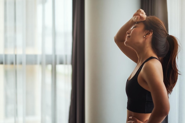 Image en gros plan d'une jeune femme asiatique fatiguée se reposant après une séance d'entraînement à la maison