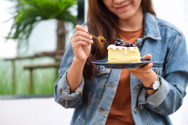 Image en gros plan d'une jeune femme mangeant un gâteau au fromage aux bleuets