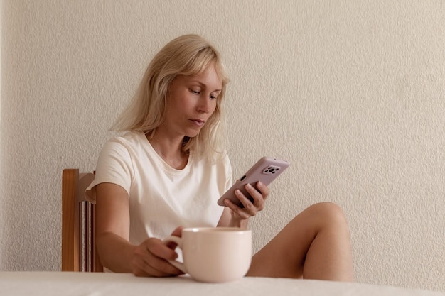 Image en gros plan d'une jolie femme assise à l'intérieur d'une maison confortable et utilisant un smartphone moderne mains féminines tapant un message texte via le concept de réseau social de téléphone portable