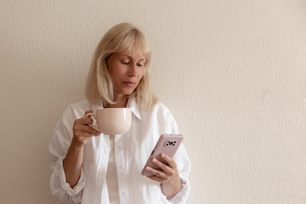 Image en gros plan d'une jolie femme assise à l'intérieur d'une maison confortable et utilisant un smartphone moderne mains féminines tapant un message texte via le concept de réseau social de téléphone portable