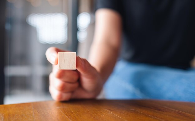 Image en gros plan d'une main choisissant et choisissant un morceau de bloc de cube en bois vierge