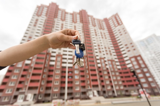 Image gros plan d'une main féminine tenant les clés du nouvel appartement.