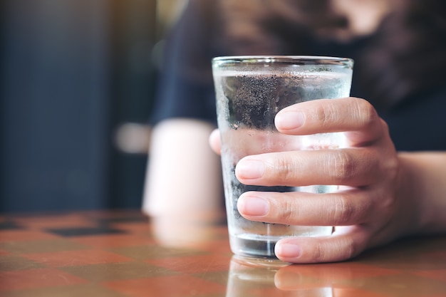 Image Gros Plan De La Main De La Femme Tenant Un Verre D'eau Froide Sur La Table