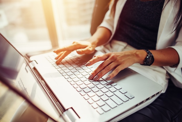 Image en gros plan des mains féminines sur le clavier. Femme travaillant sur ordinateur portable.