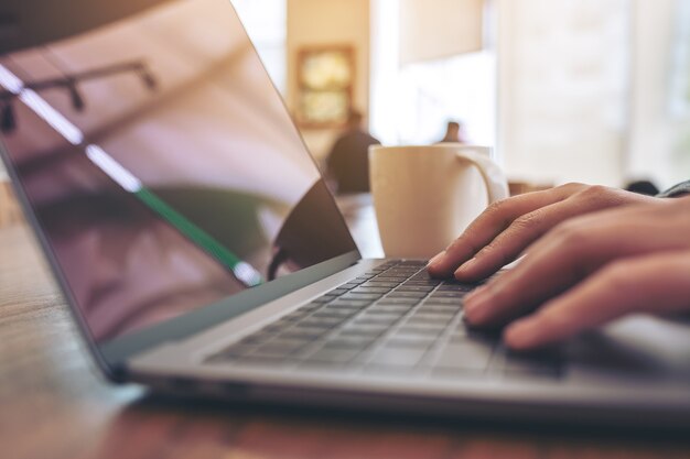 Image Gros plan des mains de la femme à l'aide et en tapant sur le clavier d'ordinateur portable sur la table