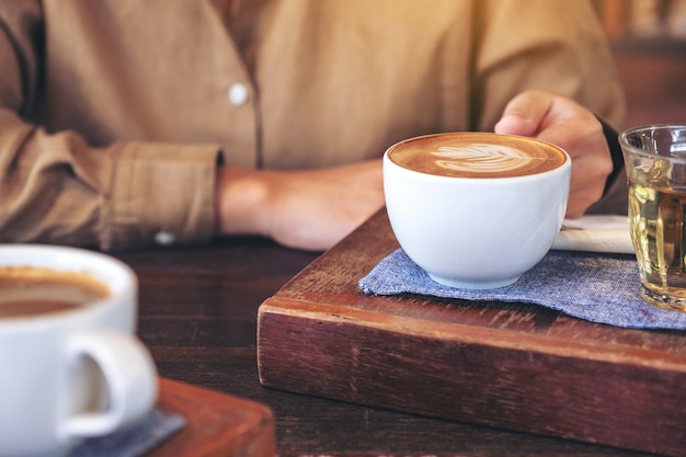 Image Gros plan des mains de femme tenant une tasse de café chaud sur la table en bois