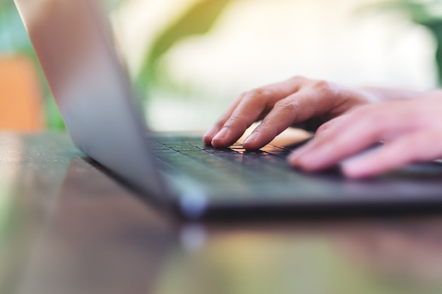 Image en gros plan des mains utilisant et tapant sur le clavier de l'ordinateur portable sur la table