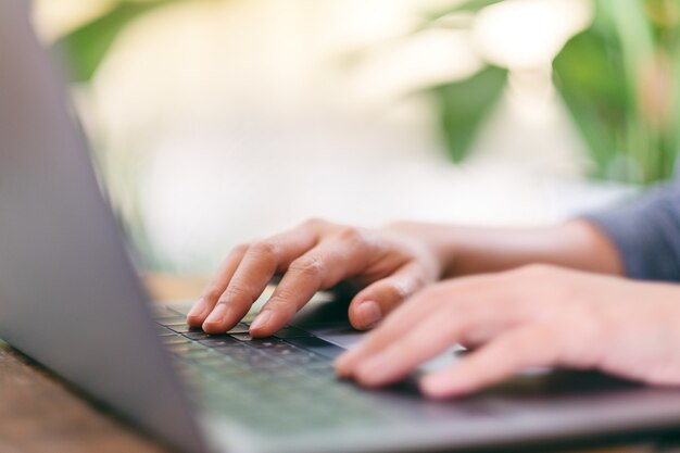 Image en gros plan des mains utilisant et tapant sur le clavier de l'ordinateur portable sur la table