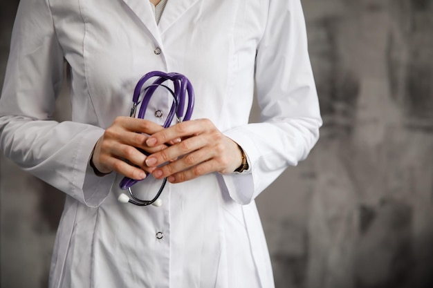 Image en gros plan d'un médecin avec un stéthoscope dans les mains sur fond d'hôpital flou