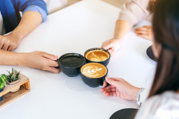 Image en gros plan de personnes appréciées pour boire et tinter des tasses de café sur la table du café