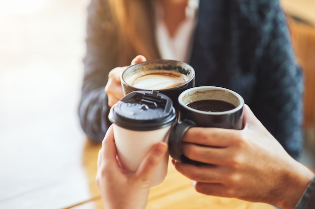 Image en gros plan de personnes appréciées pour boire et tinter des tasses de café sur la table du café