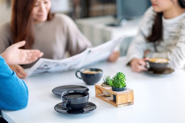 Image en gros plan de personnes parlant, lisant le journal et buvant du café ensemble le matin