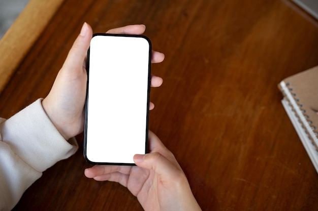 Image en haut Une femme utilisant son smartphone à un bureau Une maquette de smartphone à écran blanc
