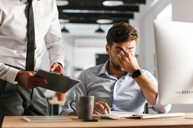 Image de l'homme d'affaires fatigué ayant des problèmes au travail alors qu'il était assis près de la table au bureau